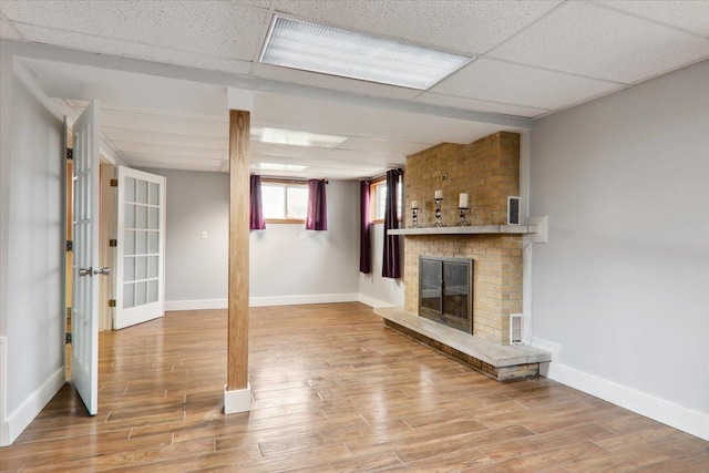 unfurnished living room with a paneled ceiling, a fireplace, and hardwood / wood-style floors