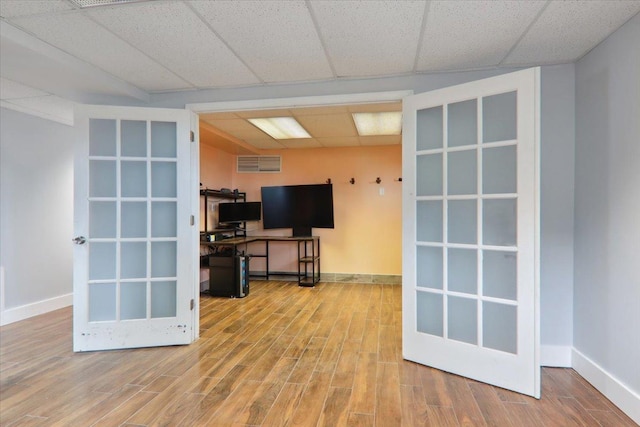 interior space featuring a paneled ceiling, french doors, and hardwood / wood-style flooring