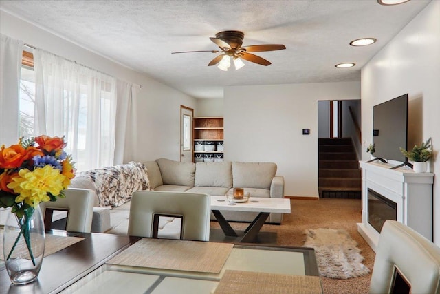 living room featuring light carpet, a textured ceiling, and ceiling fan