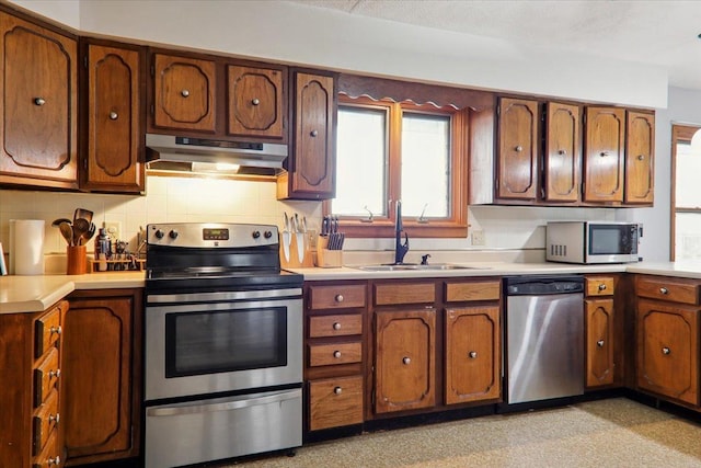 kitchen featuring appliances with stainless steel finishes, sink, extractor fan, and tasteful backsplash