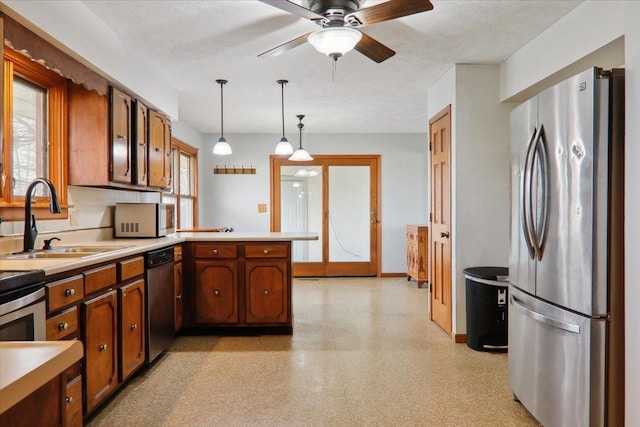 kitchen featuring sink, a textured ceiling, appliances with stainless steel finishes, decorative light fixtures, and kitchen peninsula