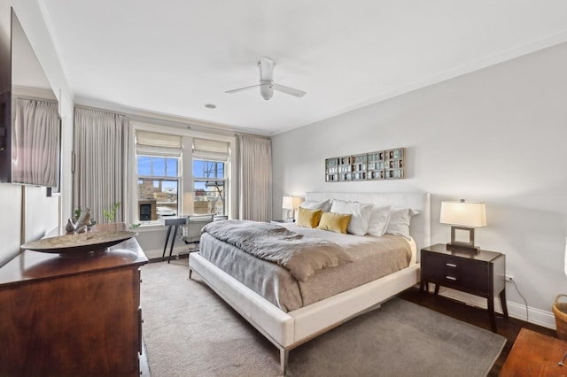 bedroom featuring crown molding, baseboards, a ceiling fan, and wood finished floors