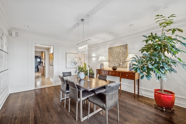 dining area with ornamental molding, a notable chandelier, and wood finished floors