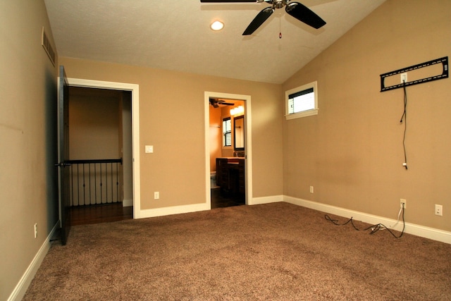 unfurnished bedroom with ensuite bathroom, dark carpet, ceiling fan, and vaulted ceiling