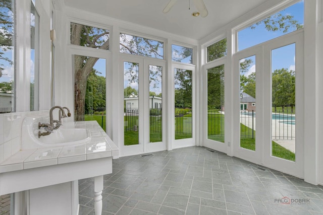 unfurnished sunroom featuring sink and ceiling fan