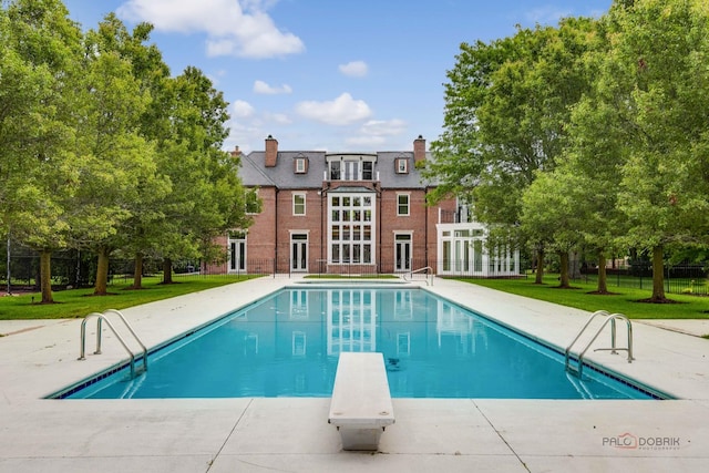 view of swimming pool featuring a diving board, a yard, and a patio area