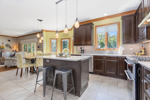 kitchen with a center island, pendant lighting, a kitchen bar, appliances with stainless steel finishes, and ornamental molding