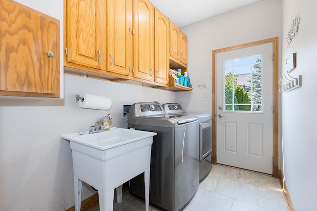 laundry area with sink, light tile patterned floors, cabinets, and independent washer and dryer