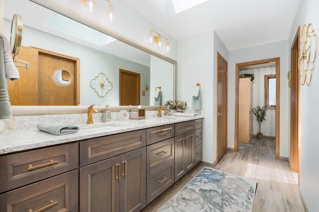 bathroom featuring vanity, wood-type flooring, and a skylight