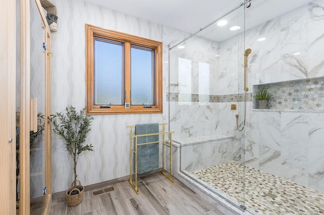 bathroom featuring hardwood / wood-style flooring and a tile shower