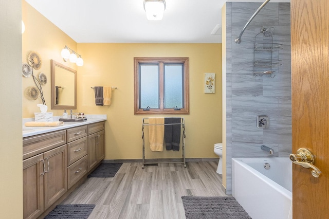 full bathroom featuring vanity, hardwood / wood-style flooring, toilet, and tiled shower / bath