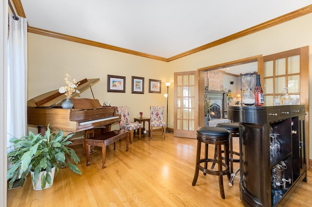 bar featuring a fireplace, french doors, light hardwood / wood-style flooring, and crown molding