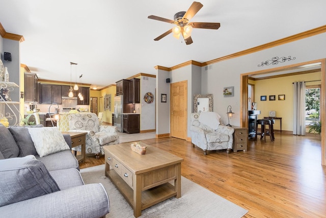 living room with light wood-type flooring, ceiling fan, and crown molding