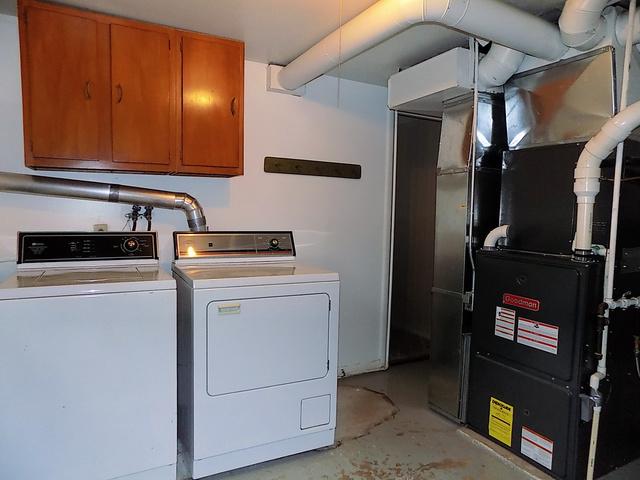 clothes washing area featuring cabinets, independent washer and dryer, and heating unit