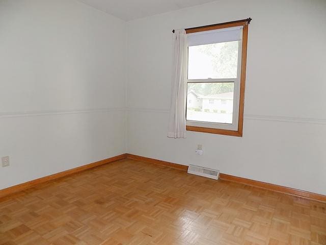 spare room with a wealth of natural light and light parquet floors