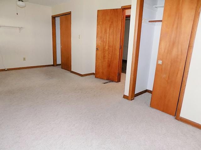 unfurnished bedroom with light carpet and two closets