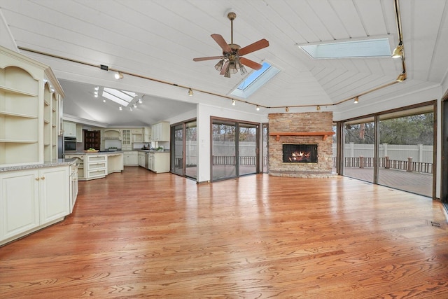 unfurnished living room with a skylight, light wood-type flooring, track lighting, and plenty of natural light