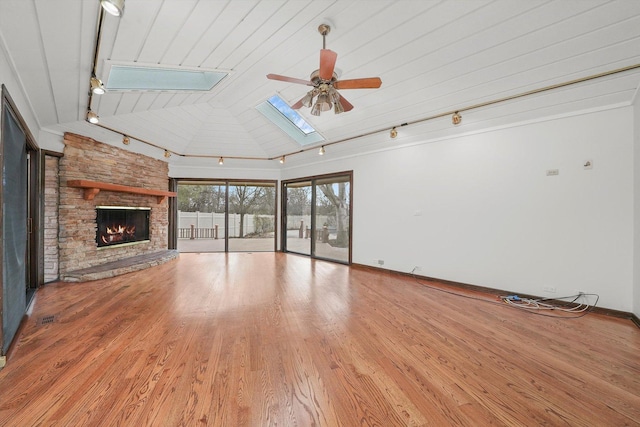 unfurnished living room with light wood-type flooring, a skylight, ceiling fan, high vaulted ceiling, and a fireplace