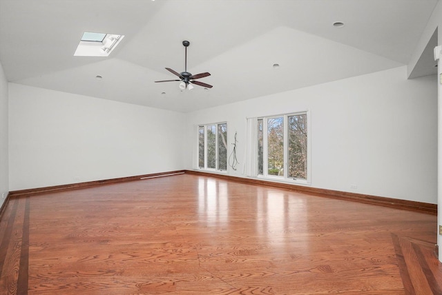 unfurnished room featuring lofted ceiling with skylight, light hardwood / wood-style flooring, and ceiling fan