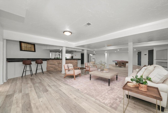 living room with light hardwood / wood-style flooring, a textured ceiling, and pool table