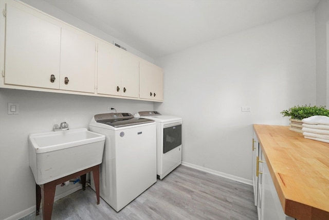 washroom with washer and clothes dryer, cabinets, light wood-type flooring, and sink