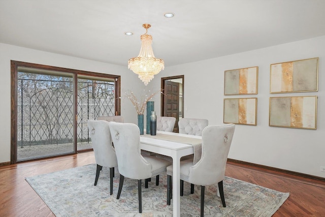 dining space featuring wood-type flooring and a notable chandelier