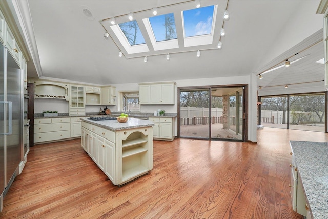 kitchen with plenty of natural light, a kitchen island, light wood-type flooring, and a skylight