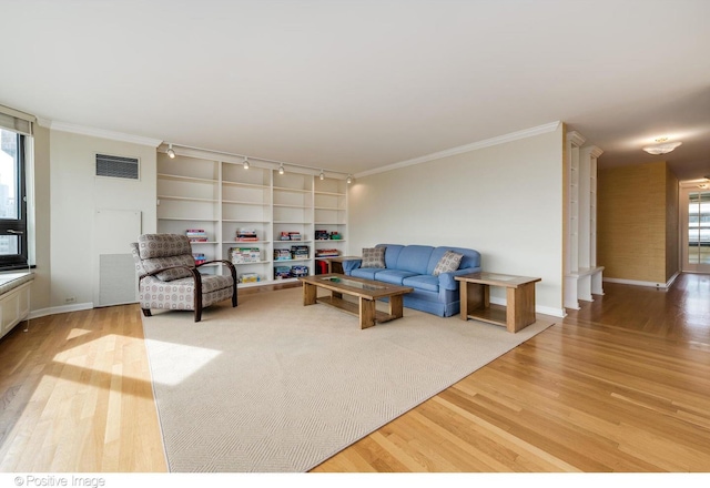 living room featuring hardwood / wood-style floors, crown molding, and built in shelves