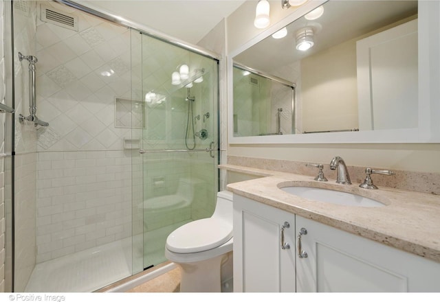 bathroom with an enclosed shower, vanity, and toilet