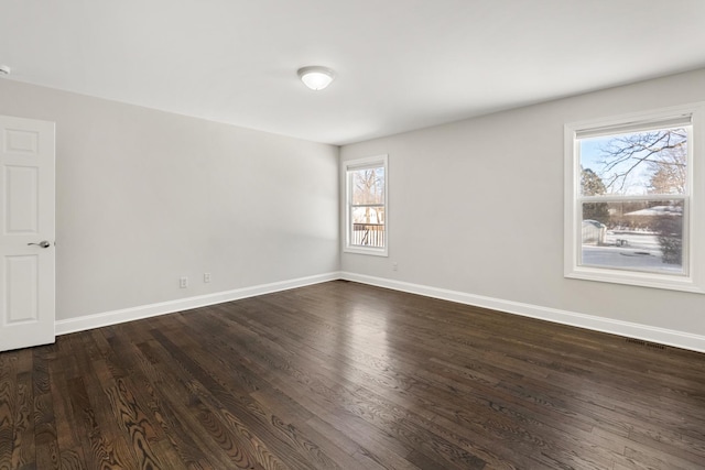 spare room featuring a wealth of natural light and dark hardwood / wood-style floors