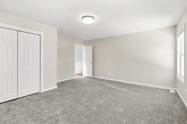 unfurnished bedroom with a closet, multiple windows, and carpet floors