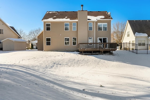 snow covered property with a storage unit and a wooden deck