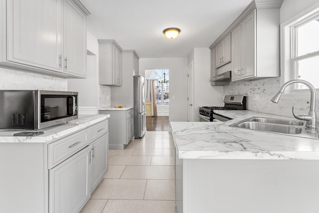 kitchen featuring appliances with stainless steel finishes, gray cabinetry, light tile patterned floors, sink, and backsplash