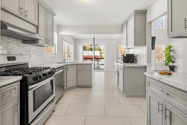 kitchen with stainless steel appliances, wall chimney range hood, sink, and gray cabinets