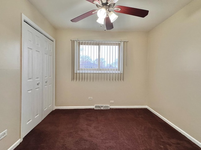 unfurnished bedroom with ceiling fan, a closet, and dark colored carpet