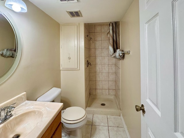 bathroom with tiled shower, vanity, tile patterned flooring, and toilet