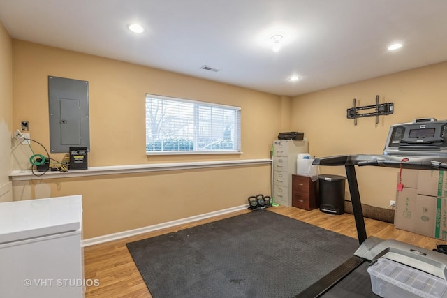 exercise room with electric panel and light hardwood / wood-style floors