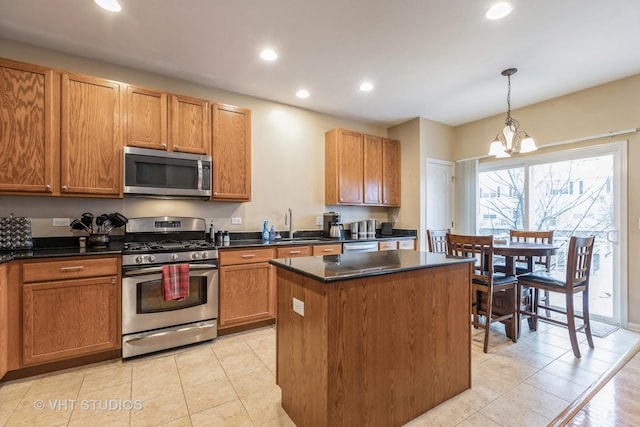 kitchen featuring light tile patterned floors, pendant lighting, a chandelier, a kitchen island, and appliances with stainless steel finishes