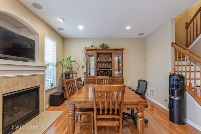 dining space with light wood-type flooring and a tiled fireplace