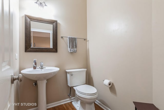 bathroom with toilet, wood-type flooring, and sink