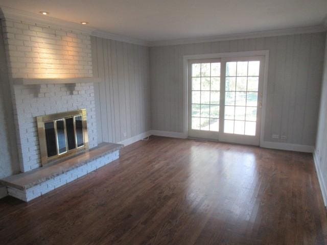 unfurnished living room featuring dark hardwood / wood-style flooring, a brick fireplace, and ornamental molding