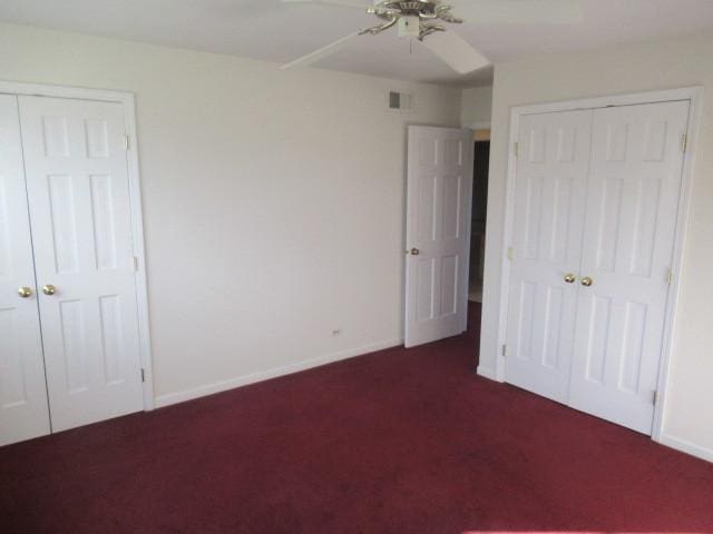 unfurnished bedroom with multiple closets, ceiling fan, and dark carpet