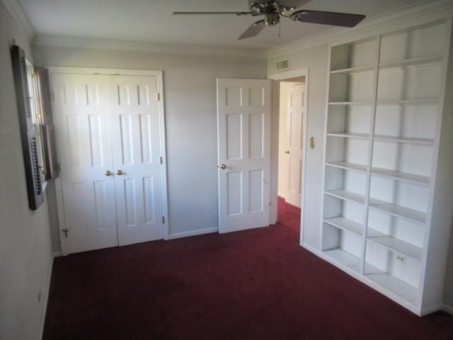 unfurnished bedroom featuring dark colored carpet, a closet, ceiling fan, and crown molding