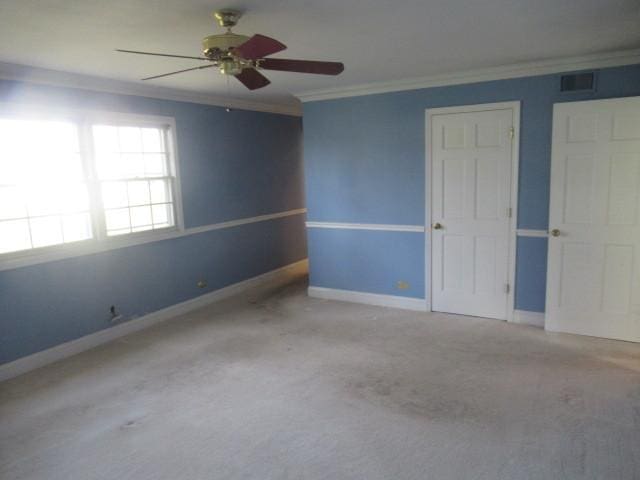 carpeted empty room with ceiling fan and crown molding