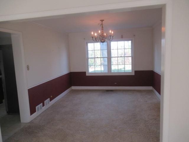 carpeted spare room featuring a notable chandelier