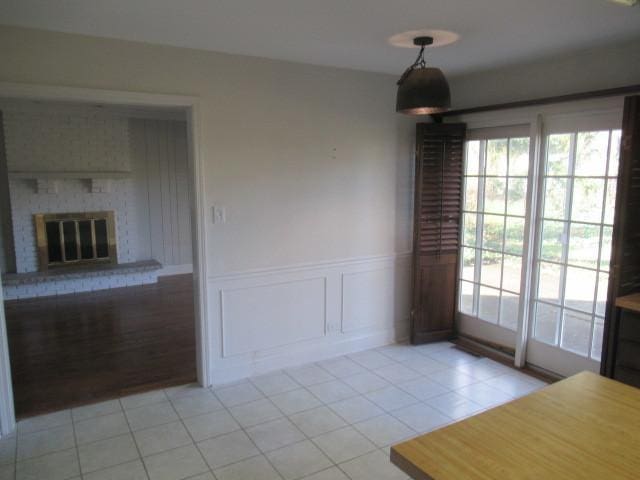 unfurnished dining area featuring a fireplace and light tile patterned floors