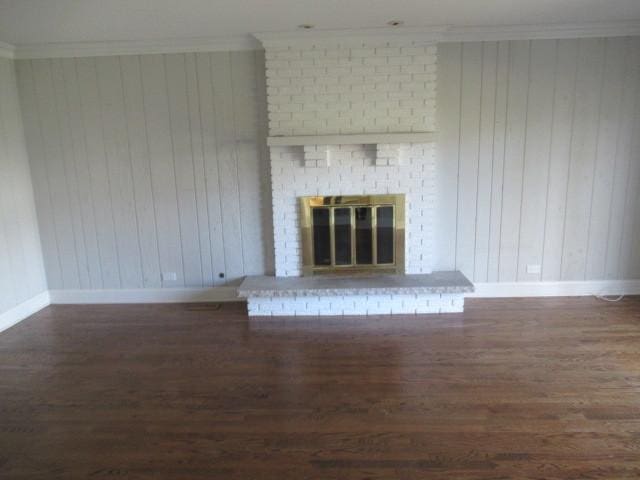 unfurnished living room featuring a fireplace, crown molding, dark hardwood / wood-style flooring, and wooden walls