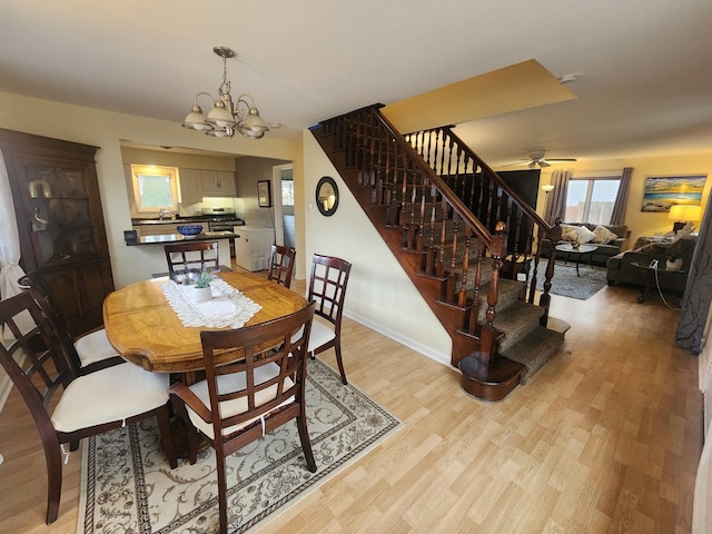 dining room with ceiling fan with notable chandelier, light hardwood / wood-style flooring, and sink