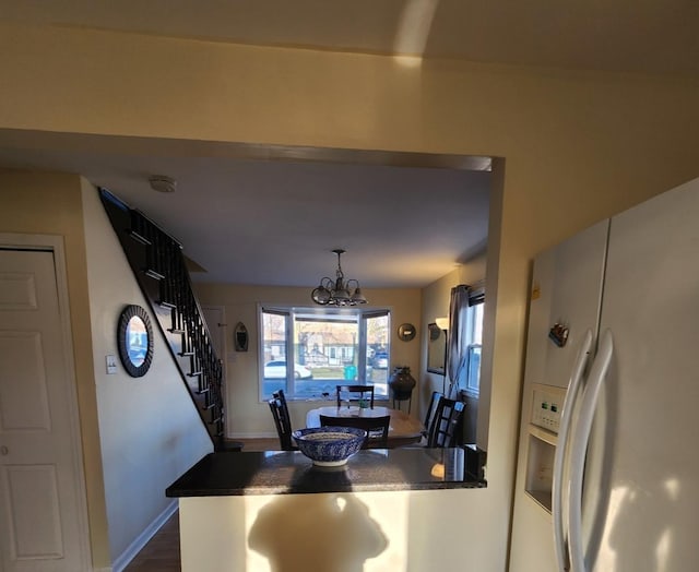 kitchen with white fridge with ice dispenser, a chandelier, and decorative light fixtures