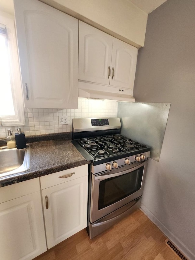 kitchen featuring white cabinetry, a wealth of natural light, and gas range